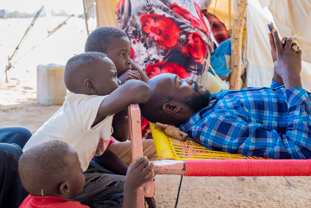 A displaced family outside a shelter in a camp in Sudan