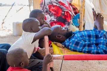 A displaced family outside a shelter in a camp in Sudan