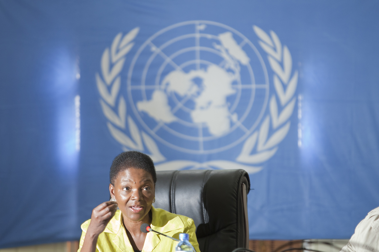Valerie Amos speaking in front of a U.N. emblem